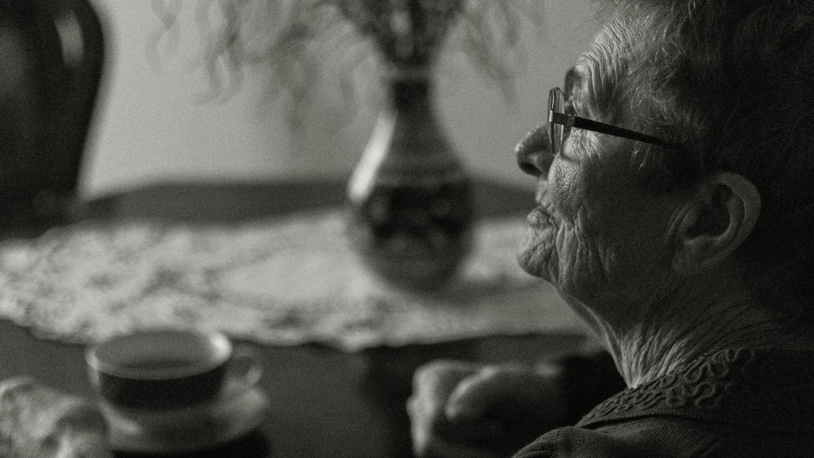 An older woman sitting quietly with a cup of coffee, reflecting