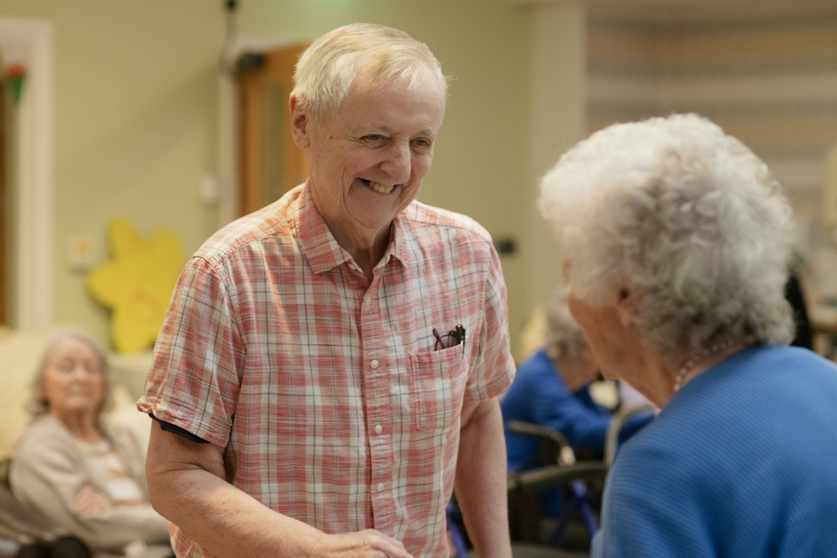 Two retirees smiling and chatting in a community room