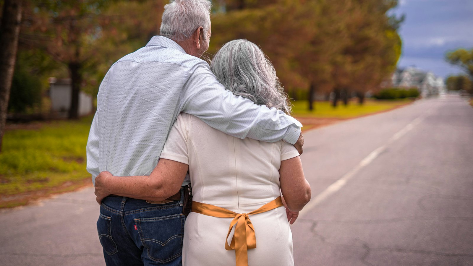 A retired couple walking arm in arm down a country road